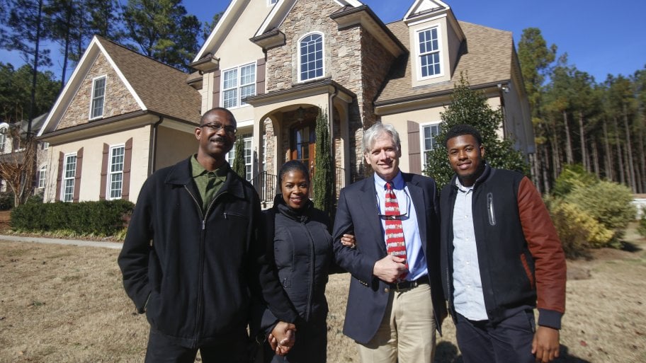 A family stands in front of a home after a sale.